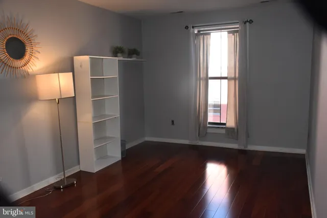 an empty room with wooden floor cabinet and windows
