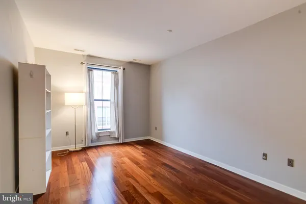 an empty room with wooden floor and window
