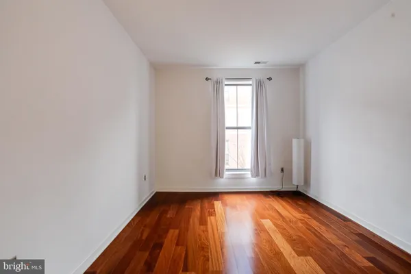 an empty room with wooden floor and fan