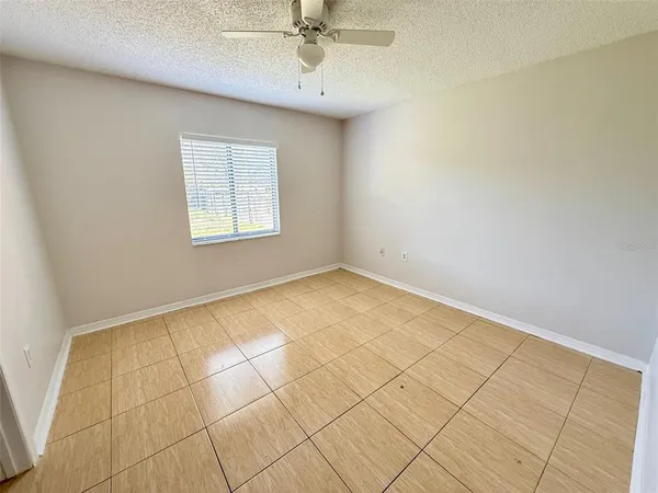 an empty room with a ceiling fan and window
