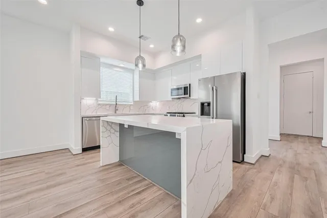 a large kitchen with cabinets wooden floor and stainless steel appliances