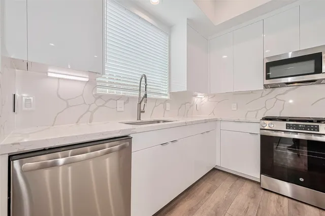 a kitchen with granite countertop white cabinets stainless steel appliances and sink