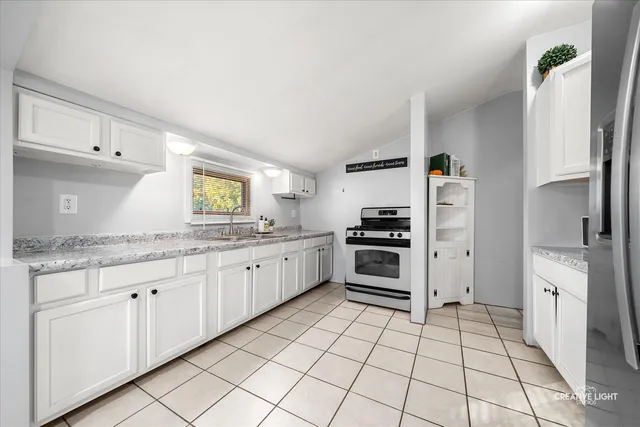 a kitchen with granite countertop a refrigerator and a stove top oven