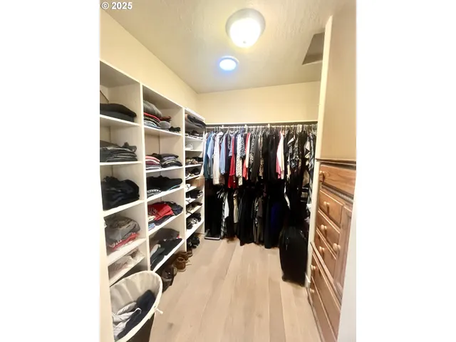a view of walk in closet with clothes and shoes