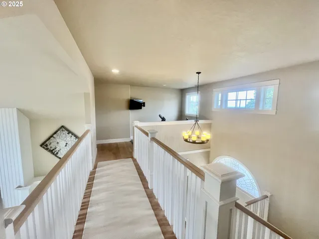 a view of a hallway with wooden floor and stairs