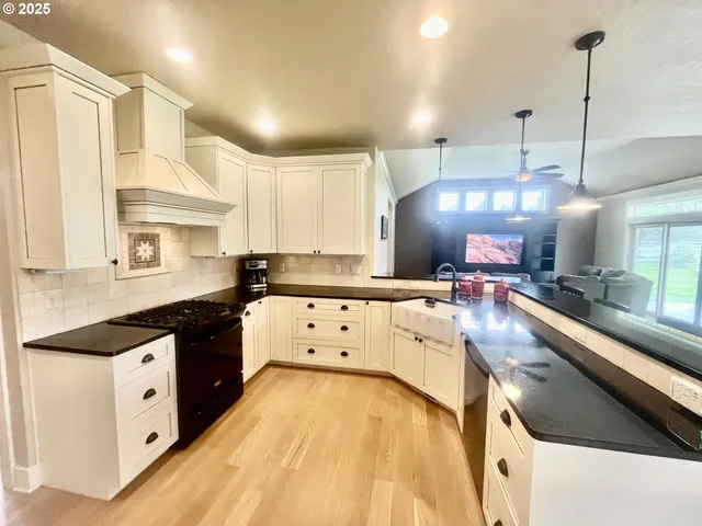 a large kitchen with a large counter top space a sink stainless steel appliances and cabinets