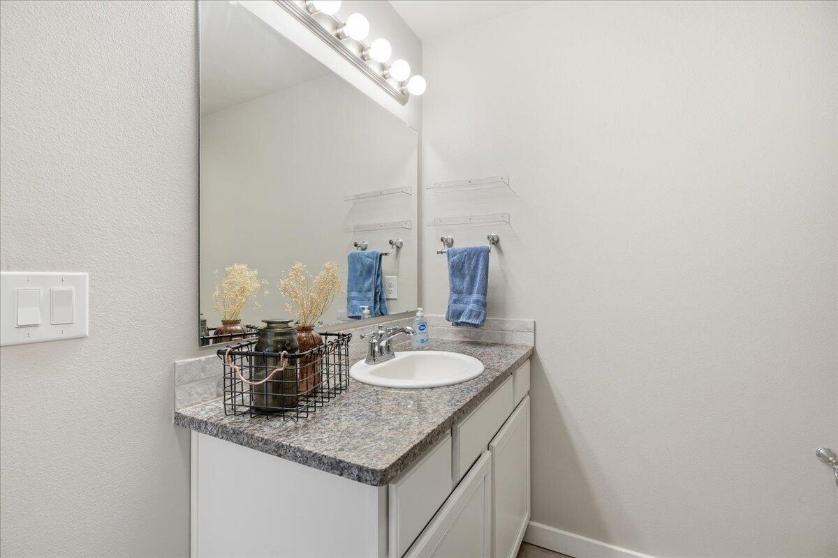 7440 32nd Street Lubbock, TX 79407 - Photo 17 of 29 a bathroom with a granite countertop sink and a mirror