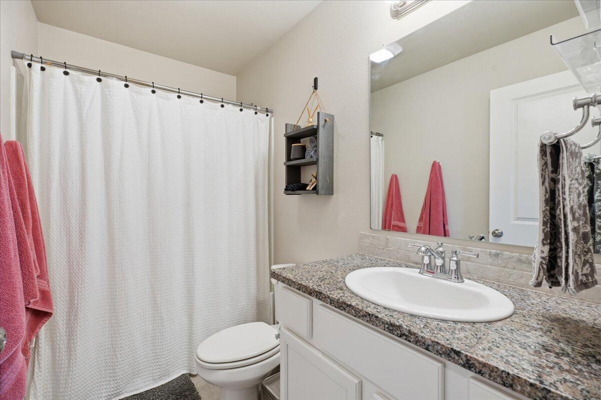 7440 32nd Street Lubbock, TX 79407 - Photo 25 of 29 a bathroom with a granite countertop sink and a mirror