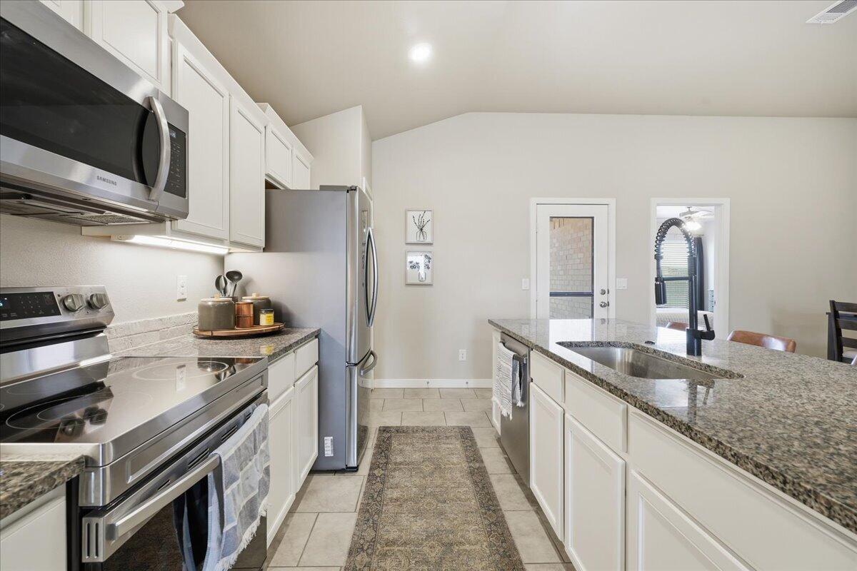 7440 32nd Street Lubbock, TX 79407 - Photo 8 of 29 a kitchen with stainless steel appliances granite countertop a sink stove and refrigerator