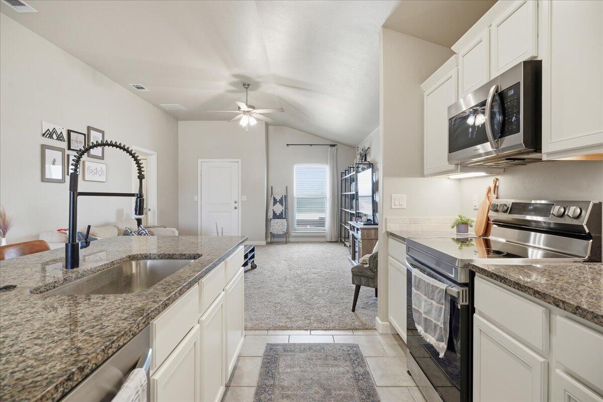 7440 32nd Street Lubbock, TX 79407 - Photo 9 of 29 a kitchen with stainless steel appliances granite countertop a sink stove and refrigerator
