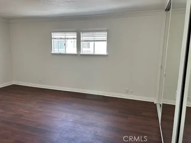 an empty room with wooden floor closet and windows