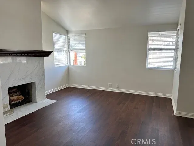 an empty room with wooden floor fireplace and windows