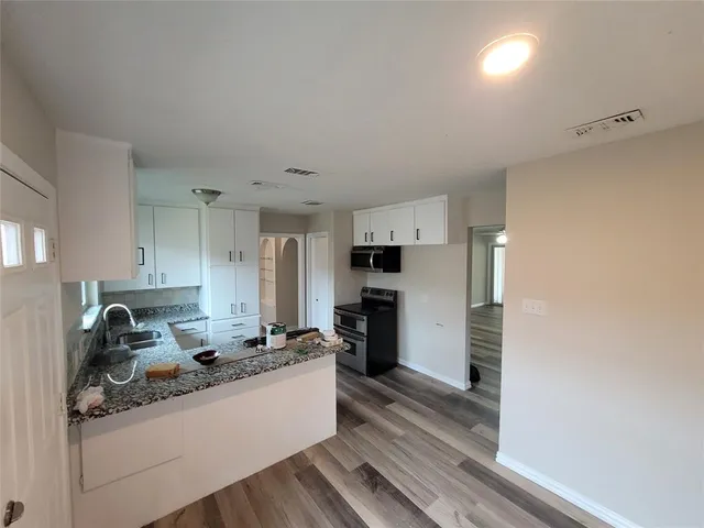 a large white kitchen with sink a refrigerator and cabinets