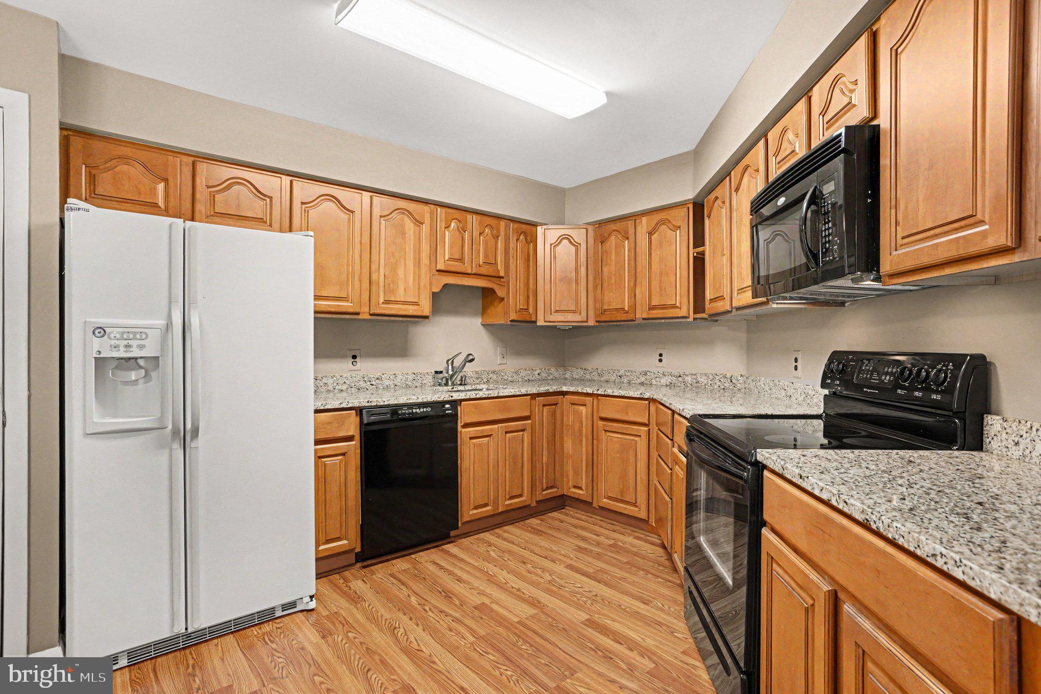 3021 Fallstaff Road, Unit 208B Baltimore, MD 21209 - Photo 11 of 25 a kitchen with stainless steel appliances granite countertop a refrigerator stove top oven a sink and dishwasher with wooden floor