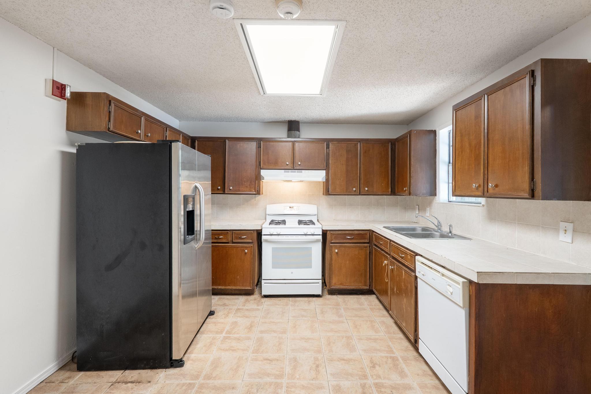 4616 East Cesar Chavez Street Austin, TX 78702 - Photo 15 of 22 a kitchen with stainless steel appliances granite countertop a refrigerator a sink dishwasher a stove with wooden cabinets