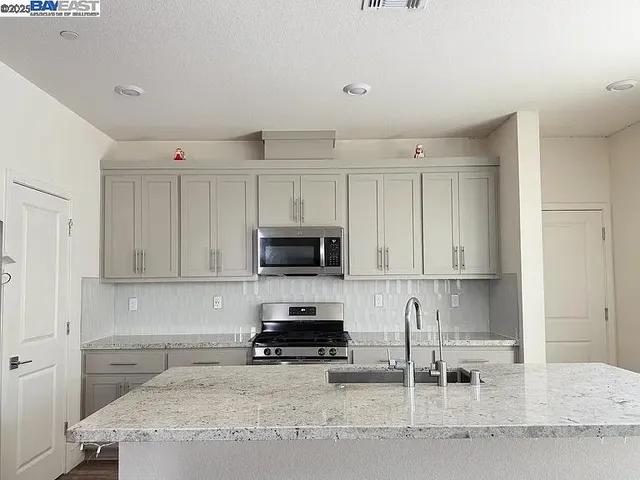 a kitchen with granite countertop a stove top oven a sink a counter space and cabinets