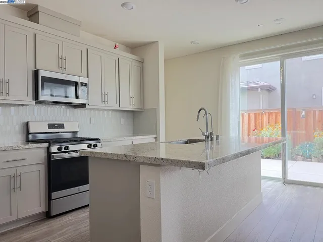 a kitchen with stainless steel appliances granite countertop a sink and cabinets with wooden floors