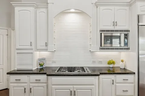 a kitchen with white cabinets and appliances