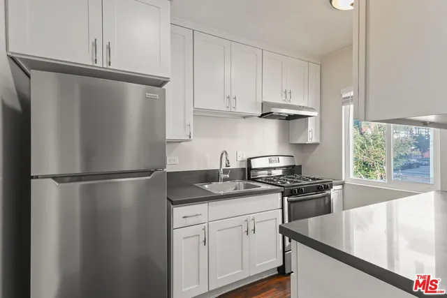 a kitchen with stainless steel appliances granite countertop a refrigerator sink stove and cabinets