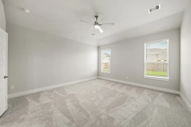 an empty room with windows and ceiling fan