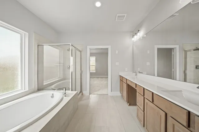 a spacious bathroom with a granite countertop tub sink shower and mirror