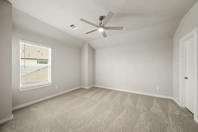 an empty room with ceiling fan and window