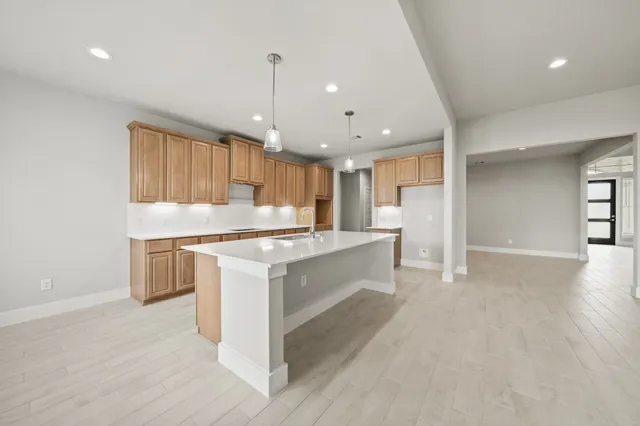 a large kitchen with a large counter top a sink stainless steel appliances and cabinets