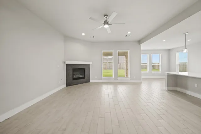 an empty room with wooden floor fireplace and windows