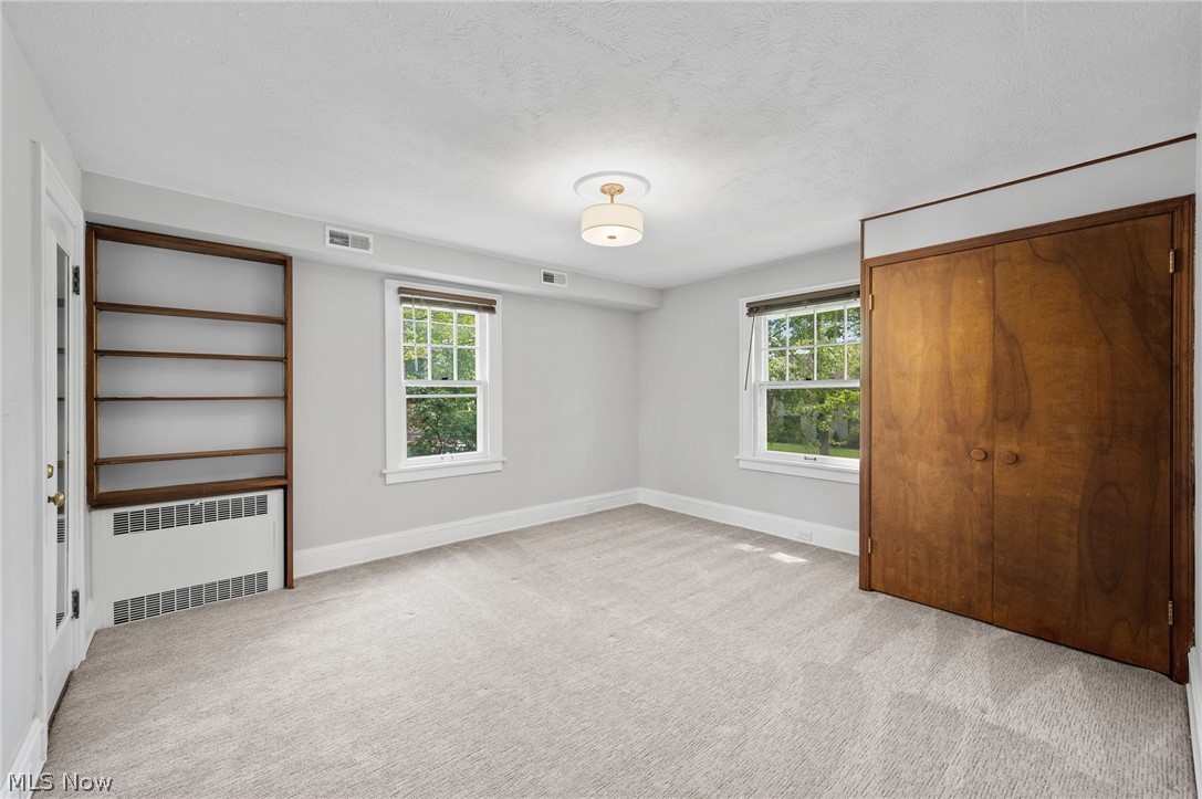 2924 Brighton Road Shaker Heights, OH 44120 - Photo 16 of 31 Unfurnished bedroom with radiator, multiple windows, light colored carpet, and a textured ceiling