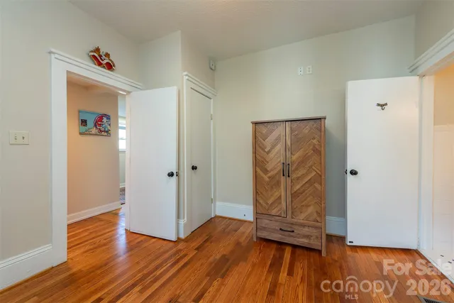 a view of an empty room with wooden floor and closet