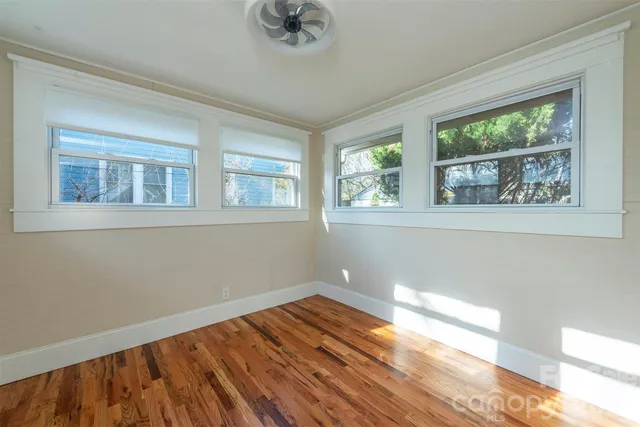 a view of empty room with wooden floor and fan