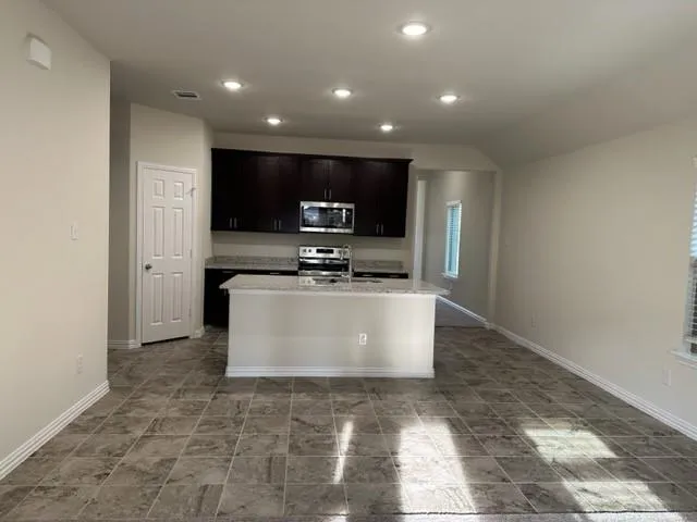 a view of kitchen with stainless steel appliances a stove a microwave a sink and a refrigerator