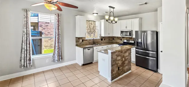 a kitchen with stainless steel appliances granite countertop a stove a refrigerator and a sink