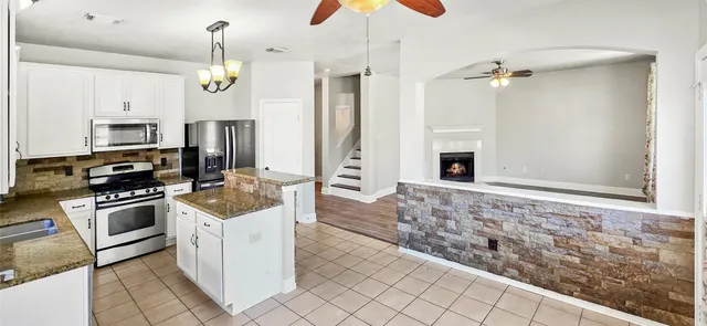a kitchen with stainless steel appliances granite countertop a stove a sink and a refrigerator
