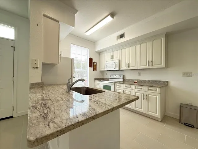 a kitchen with granite countertop a sink a stove and cabinets