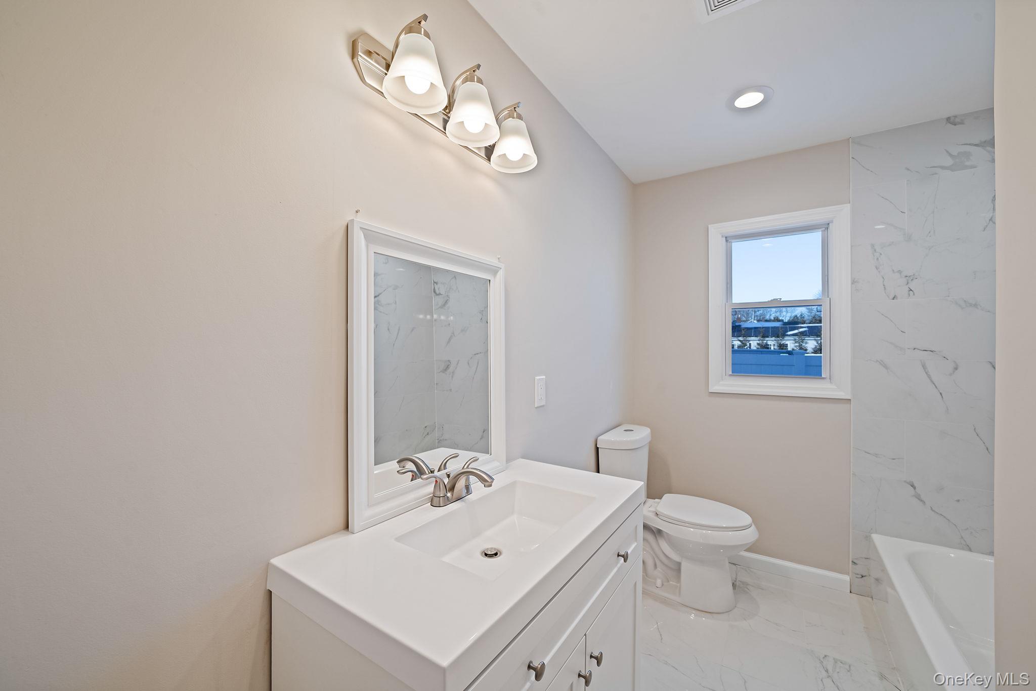 247 Rider Avenue Patchogue, NY 11772 - Photo 22 of 25 a bathroom with a toilet a sink and mirror