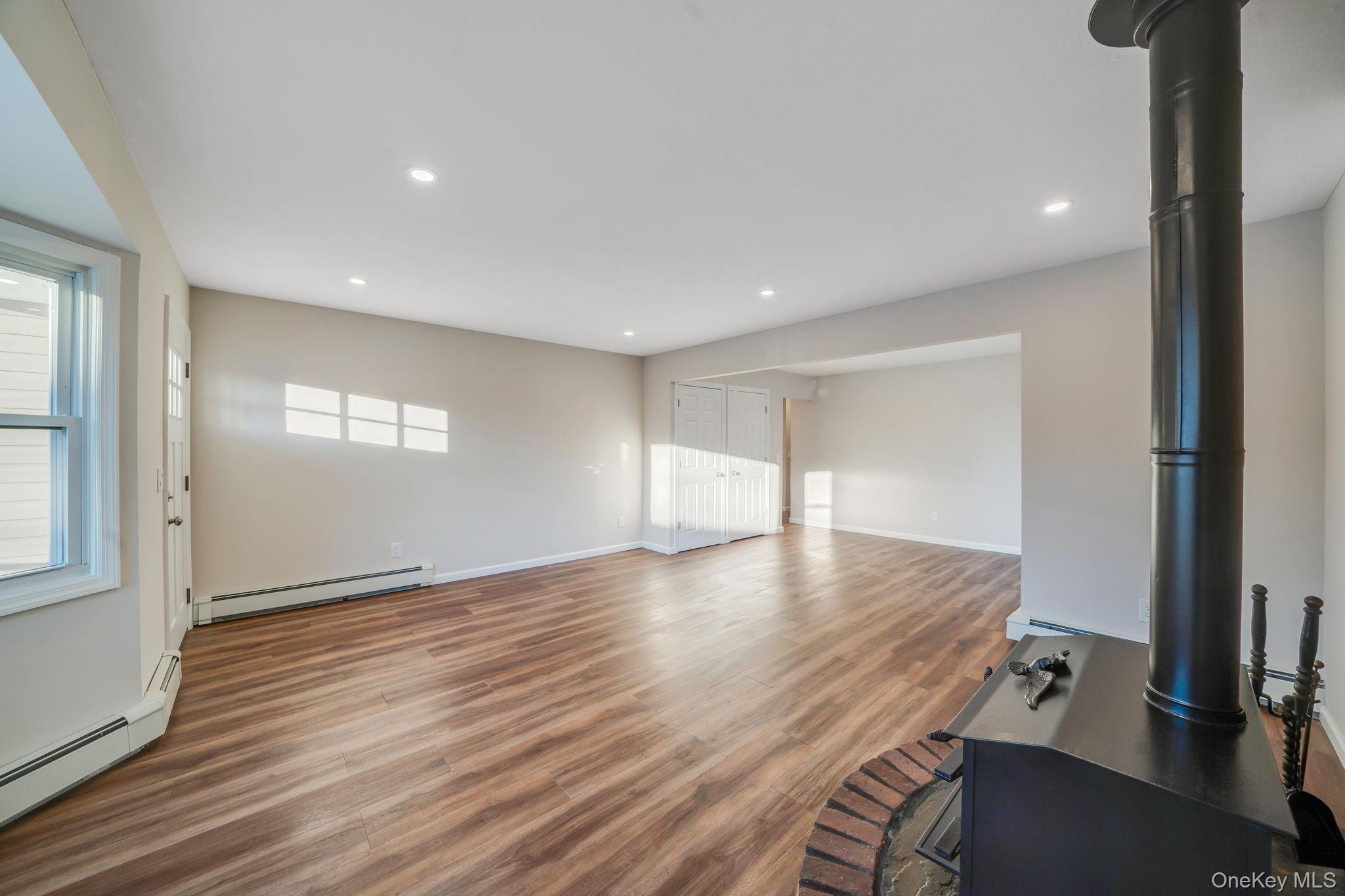 247 Rider Avenue Patchogue, NY 11772 - Photo 7 of 25 an empty room with wooden floor and windows
