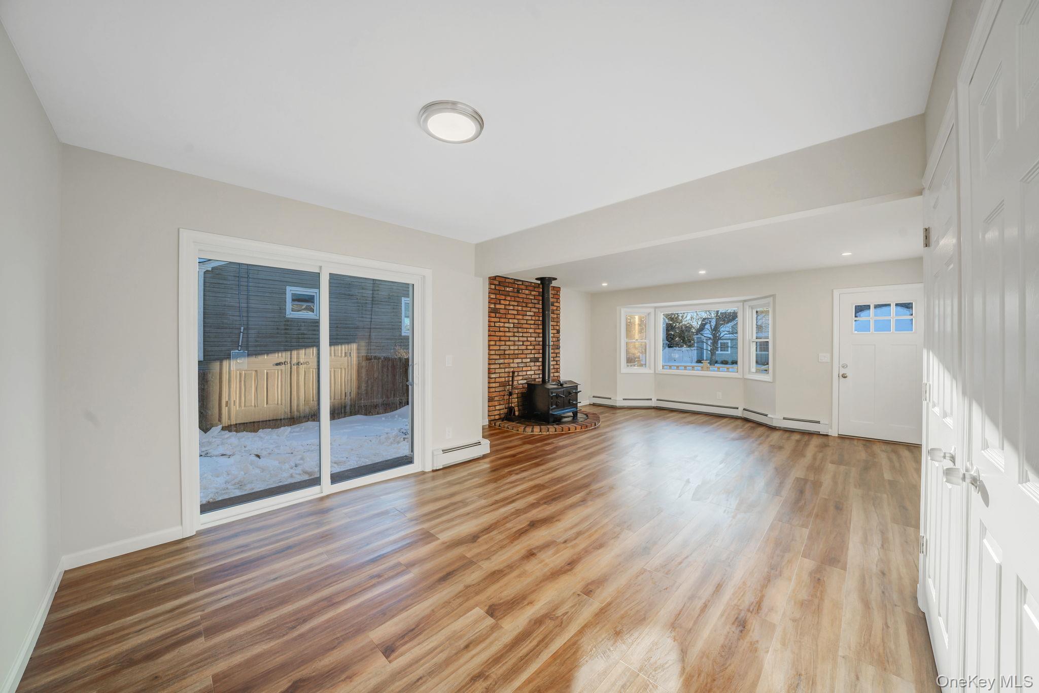 247 Rider Avenue Patchogue, NY 11772 - Photo 9 of 25 an empty room with wooden floor and windows