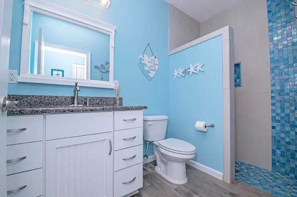 a bathroom with a granite countertop toilet sink and mirror
