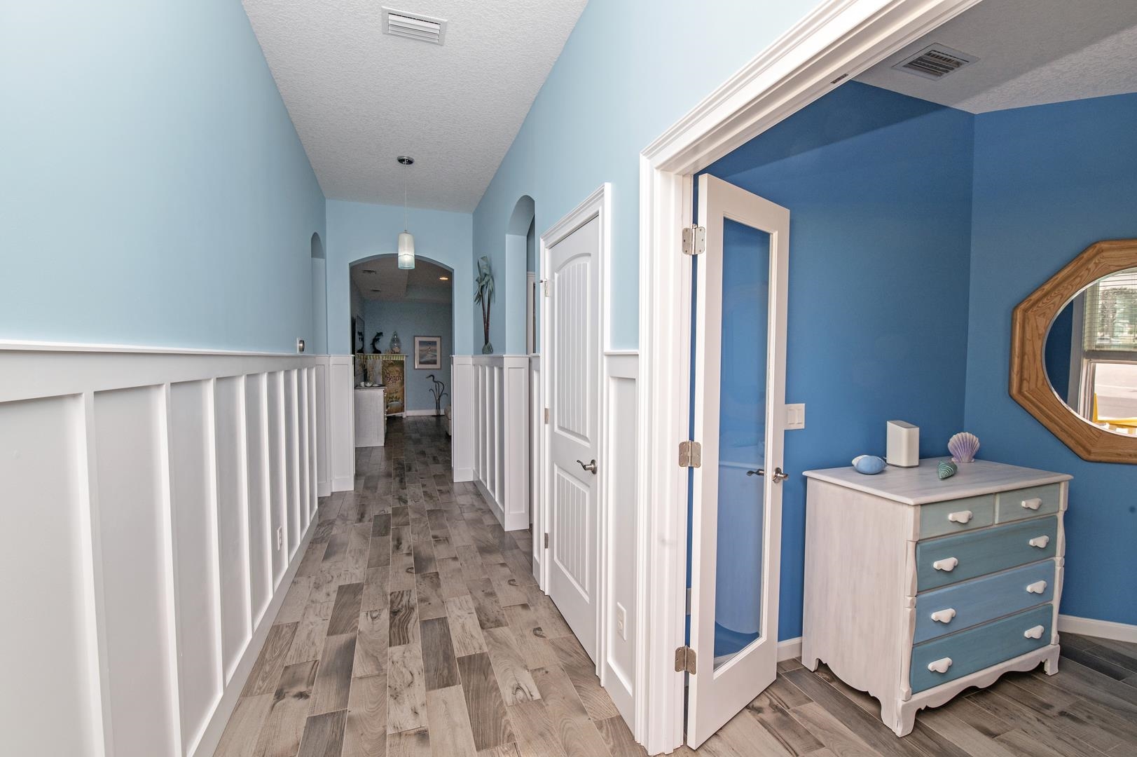 6056 Costanero Road St. Augustine, FL 32080 - Photo 15 of 30 Corridor with arched walkways, light wood-style flooring, a textured ceiling, and a wainscoted wall