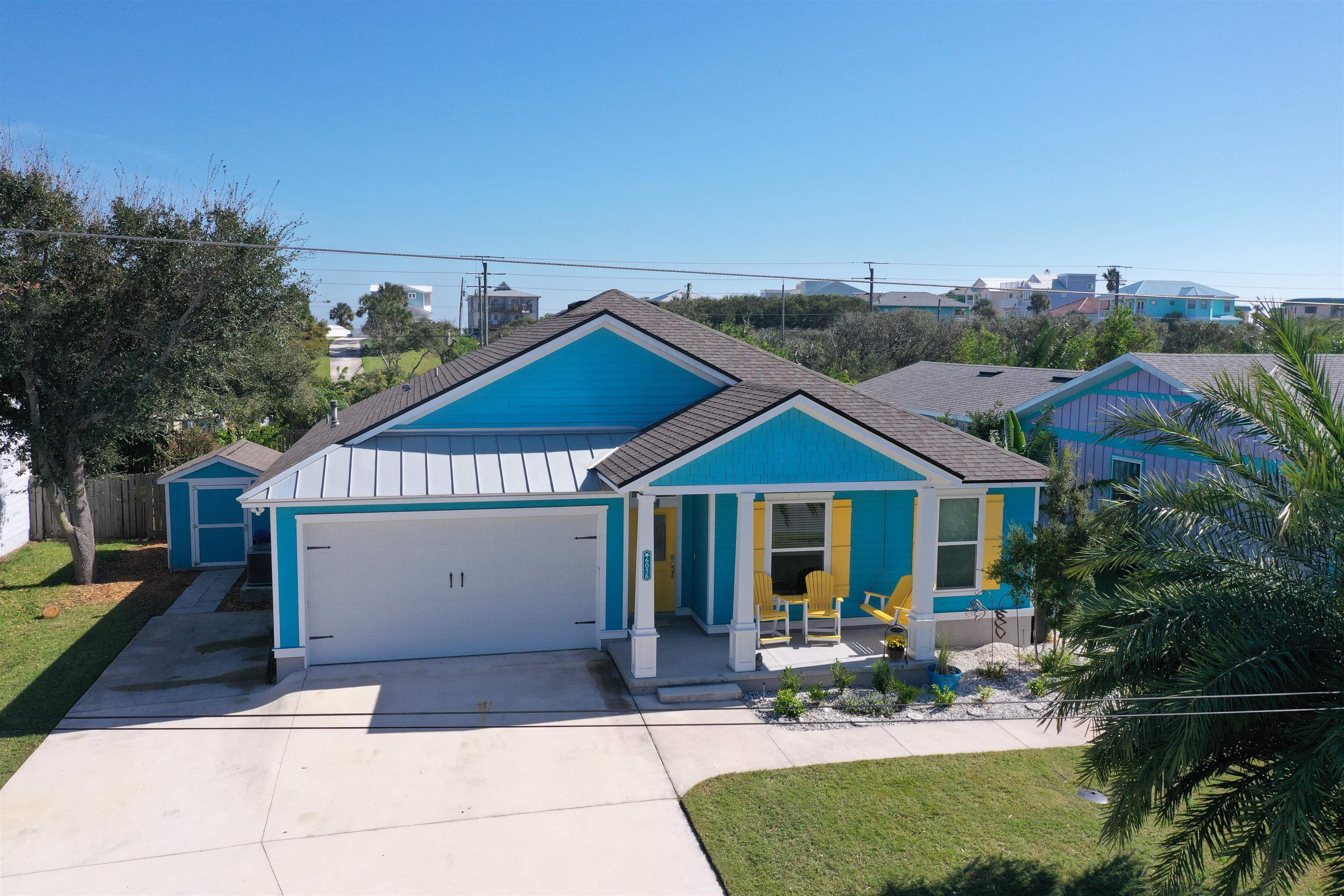 6056 Costanero Road St. Augustine, FL 32080 - Photo 2 of 30 View of front of house featuring covered porch, a standing seam roof, driveway, an attached garage, and a front yard