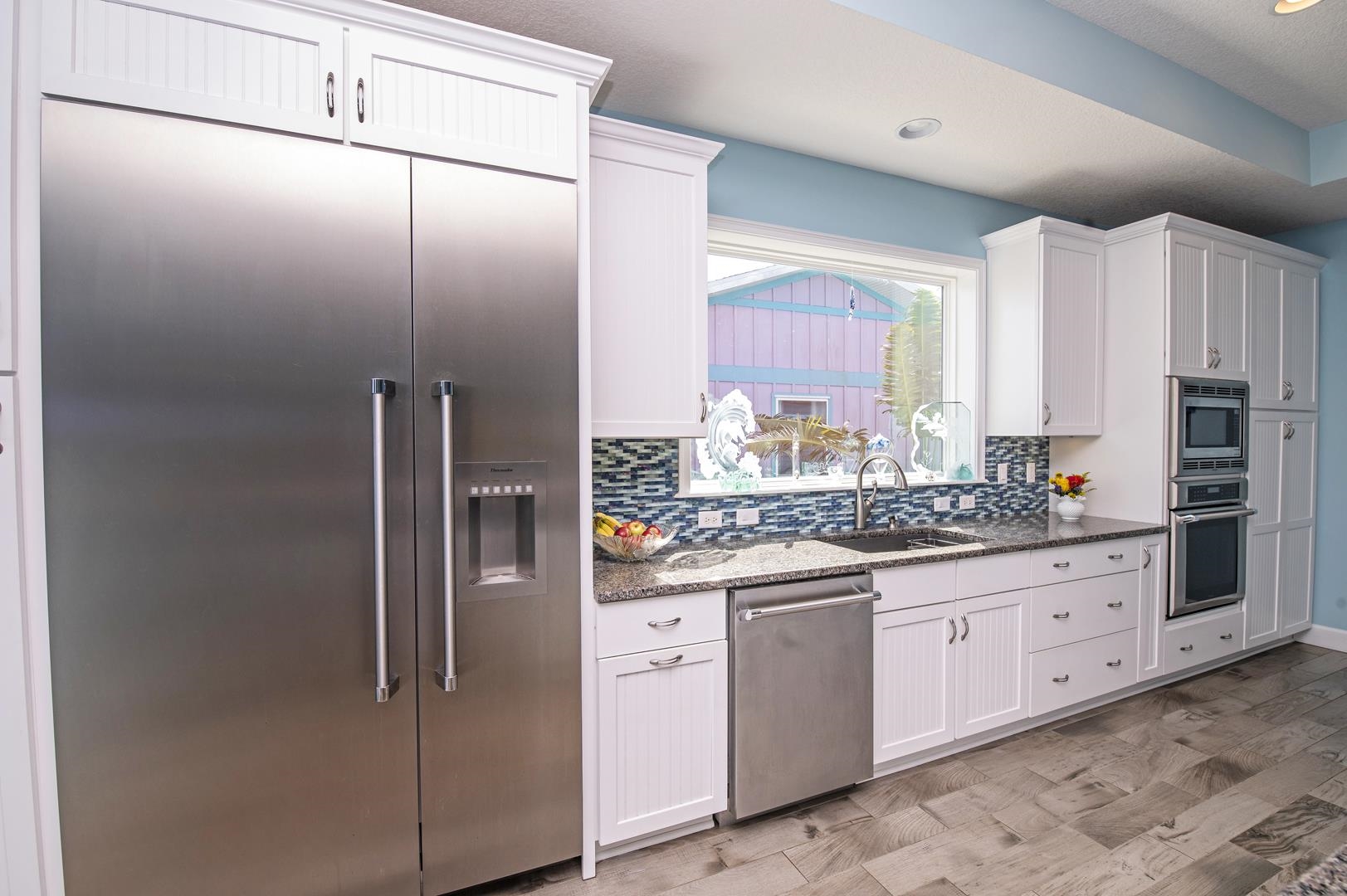 6056 Costanero Road St. Augustine, FL 32080 - Photo 5 of 30 Kitchen featuring built in appliances, dark stone counters, light wood-style flooring, white cabinetry, and tasteful backsplash