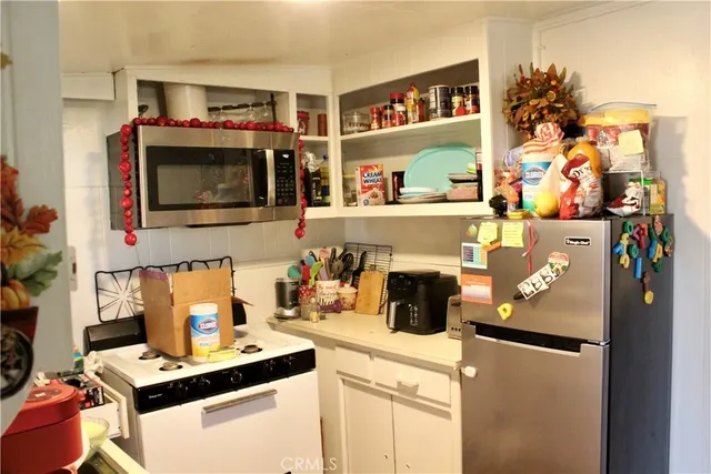 a living room with stainless steel appliances furniture and a flat screen tv