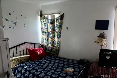 a bedroom with a bed and a flat tv screen on a dresser