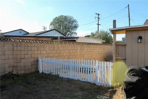 a view of a brick house with a small yard and a wooden deck