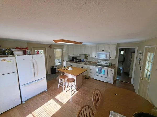 a kitchen with a refrigerator a stove a sink dishwasher and a dining table with wooden floor