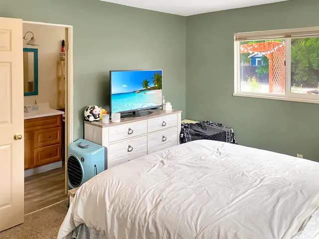 a bedroom with a bed and a flat tv screen on dresser