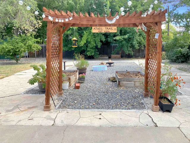a backyard of a house with table and chairs under an umbrella