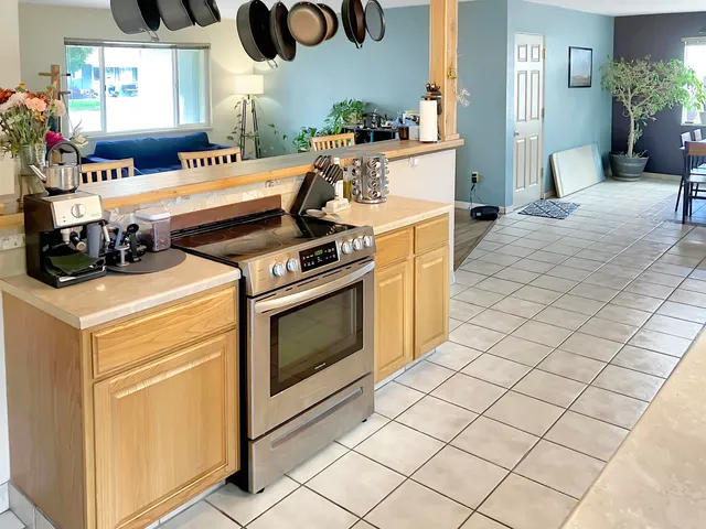 a kitchen with stainless steel appliances a stove a sink and white cabinets with wooden floor