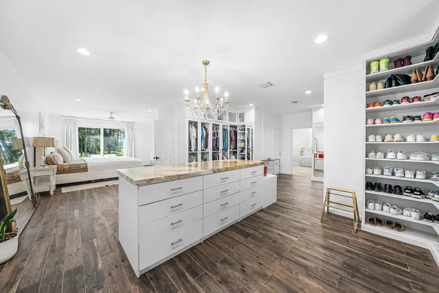 a bedroom with a bed a flat screen tv potted plant on the dresser and a window